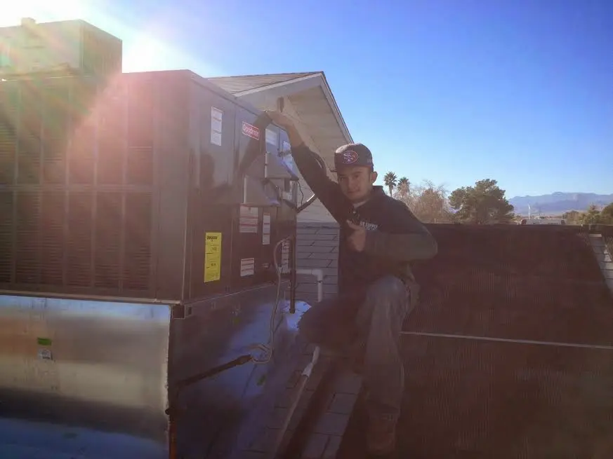 HVAC technician performing Air Duct Repair on a rooftop unit in Elk City
